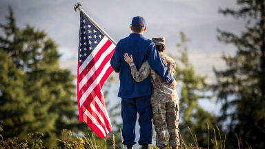 Service member couple holding an American flag.